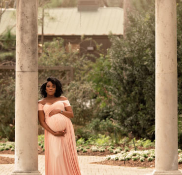 expecting mother standing in garden balancing work and mommyhood