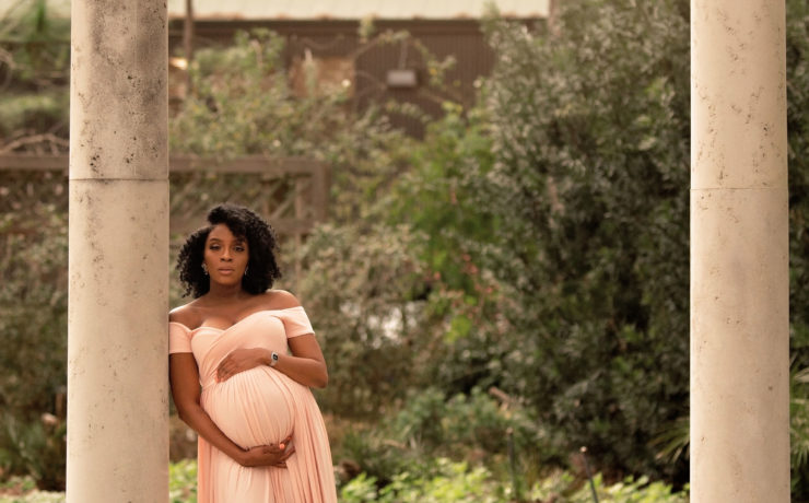 expecting mother standing in garden balancing work and mommyhood