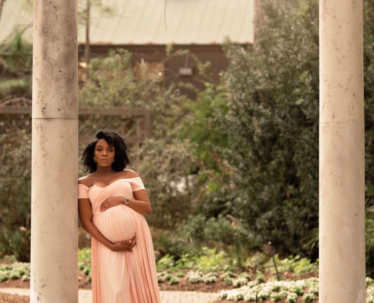 expecting mother standing in garden balancing work and mommyhood